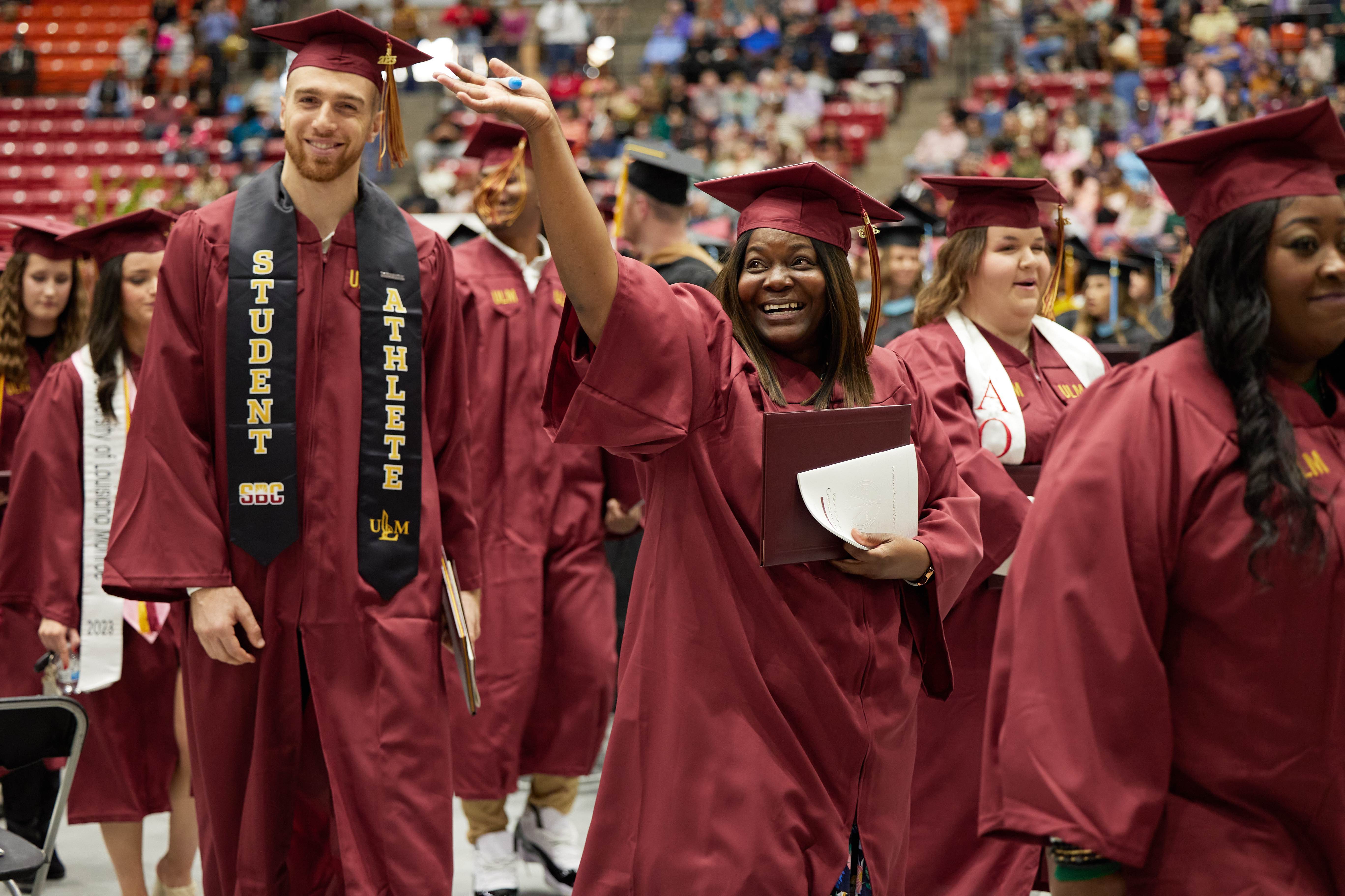 Students at commencement leaving the ceremony for the recessional, celebrating and waving to friends and family