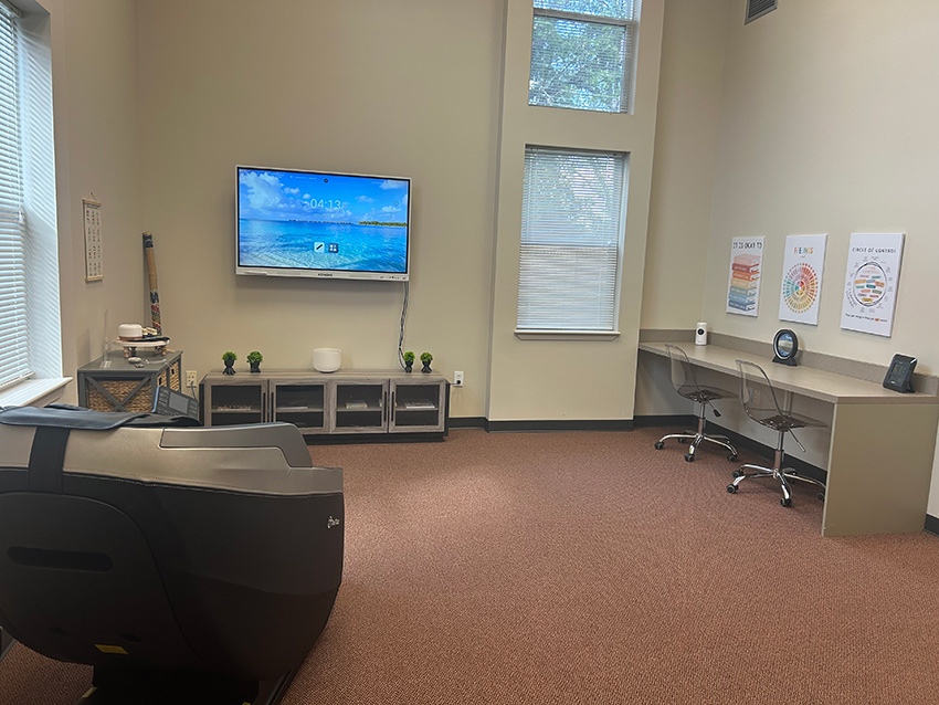 interior of room with large screen display, desk area, and cushioned lounge