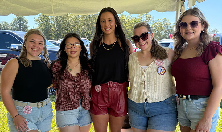 Five KE members under tent at ULM College of Pharmacy tailgate.