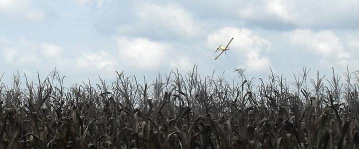 photo of crop duster plane in sky over field