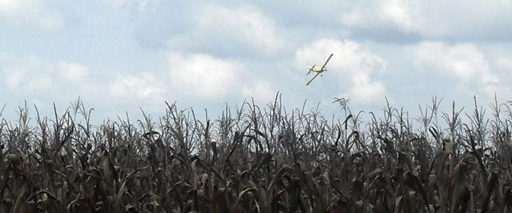 photo of crop duster plane in sky over field