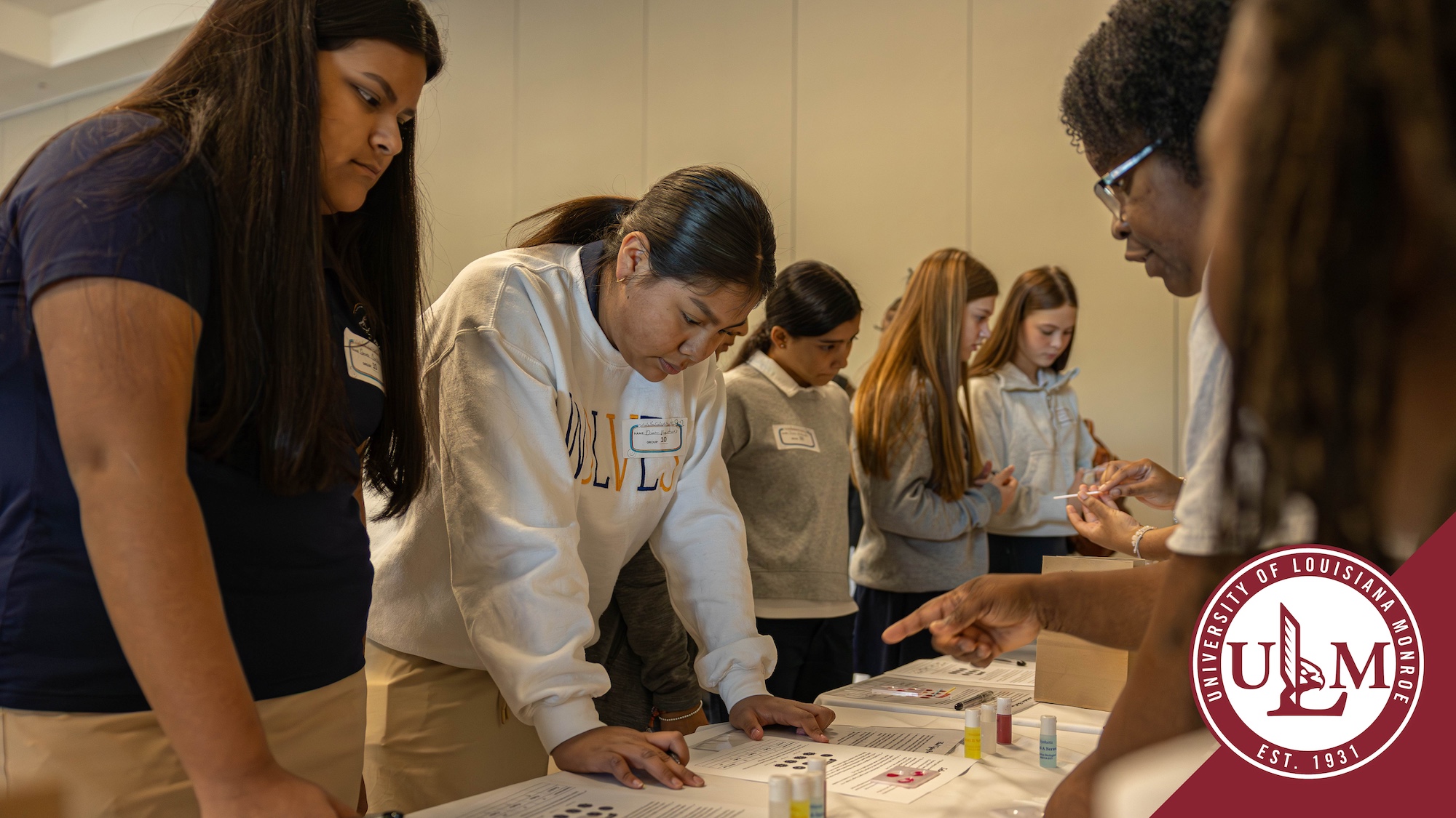 Middle school students stand at a table to learn about blood typing at Get Into the Guts of Healthcare event.