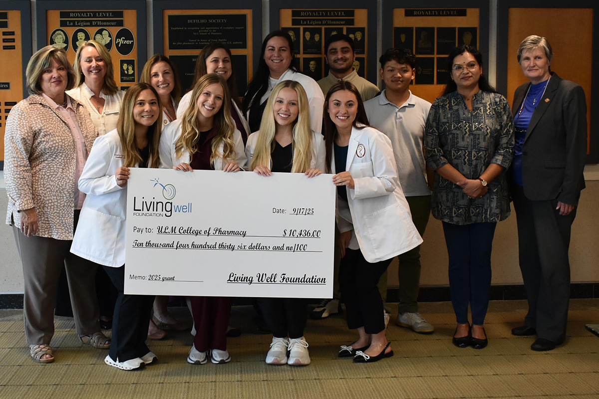 A group of people smiling holding a large check. 