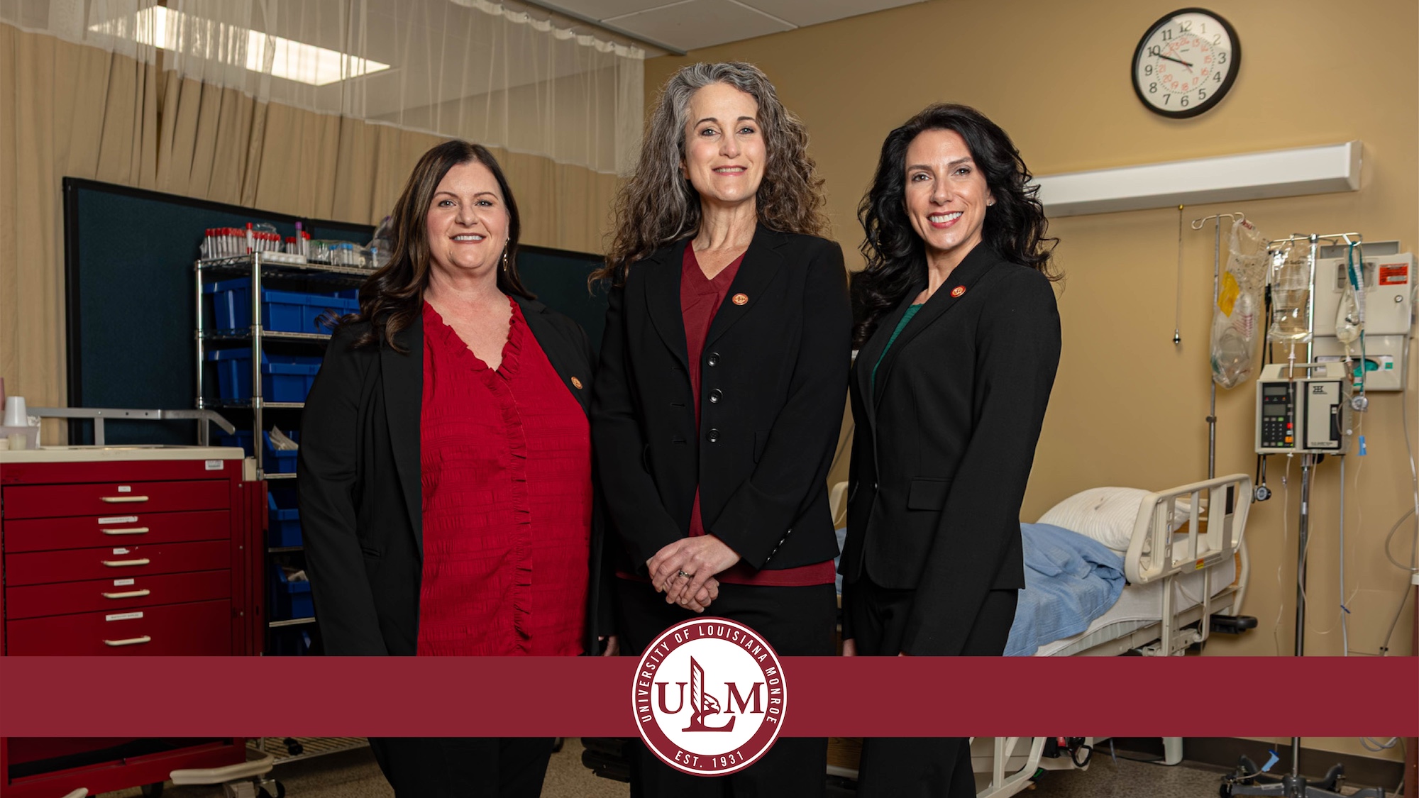 Three women smile and pose in a medical setting.