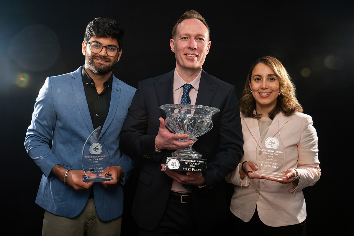 Three people standing in a row holding trophies