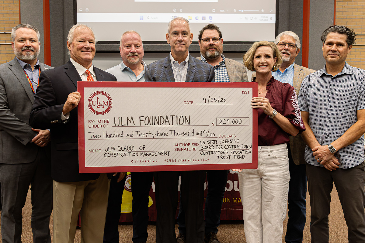 A group of people stand and smile with a large check. 