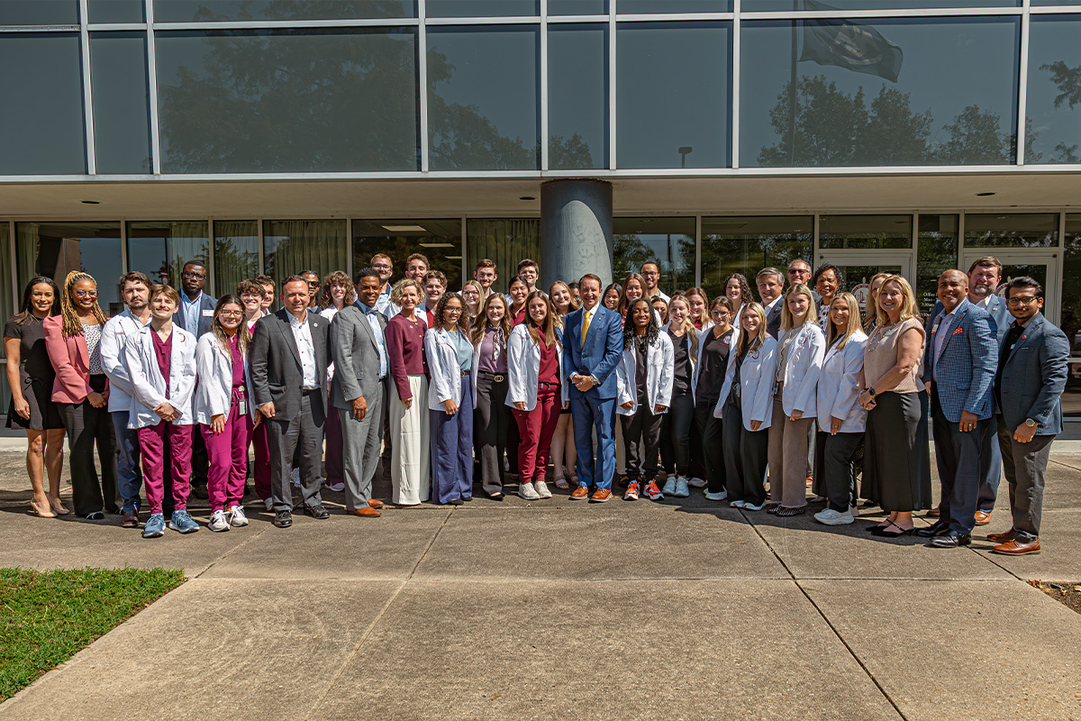 A large group of people pose in front of a building. 