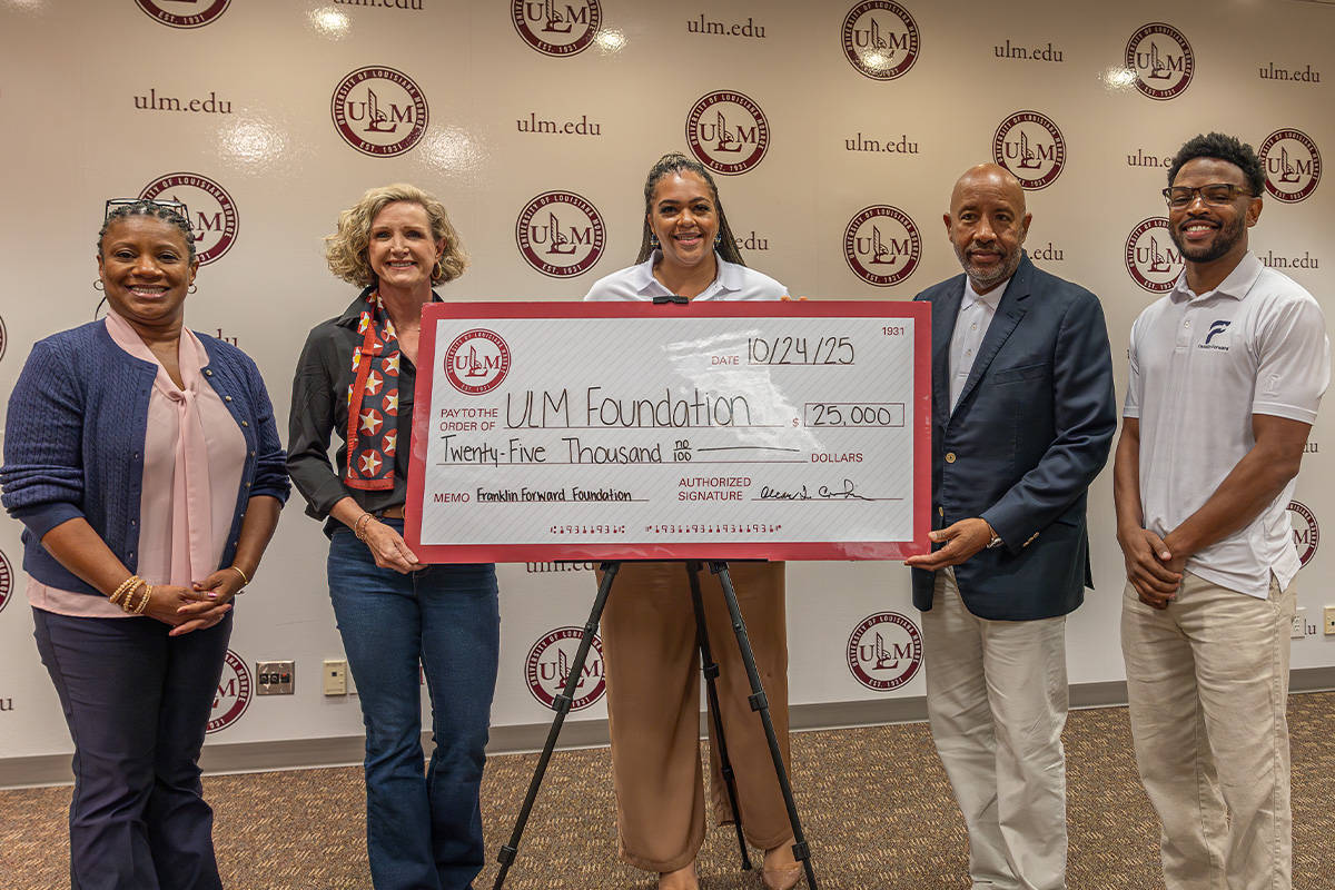 A group of people smiling and standing behind a large check. 