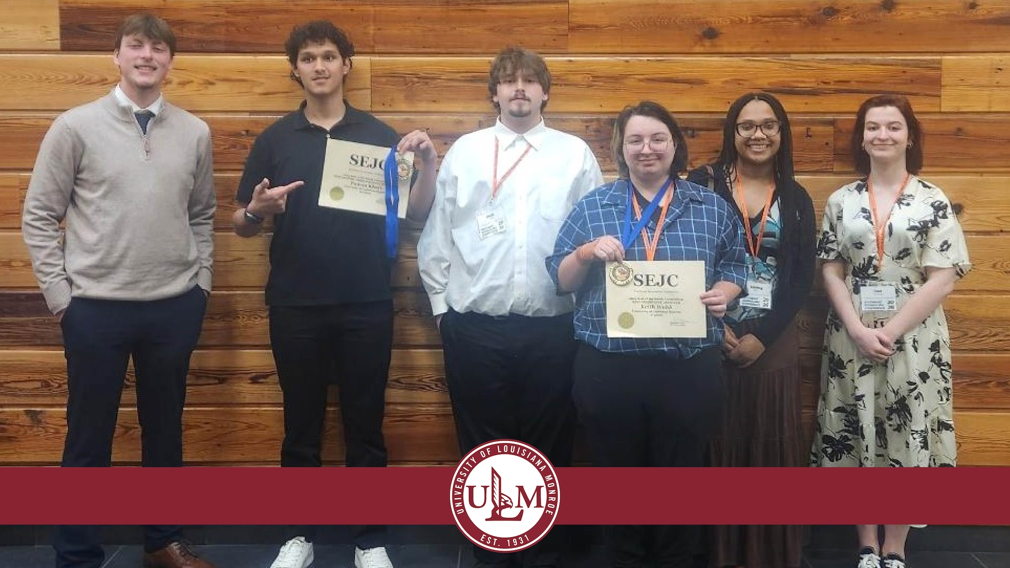 A group of people standing in a row smiling. 