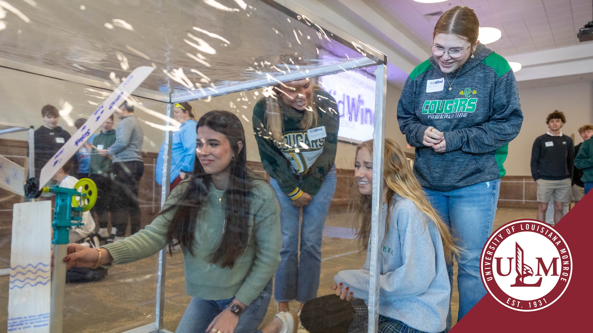 Four middle school students test a model wind turbine.