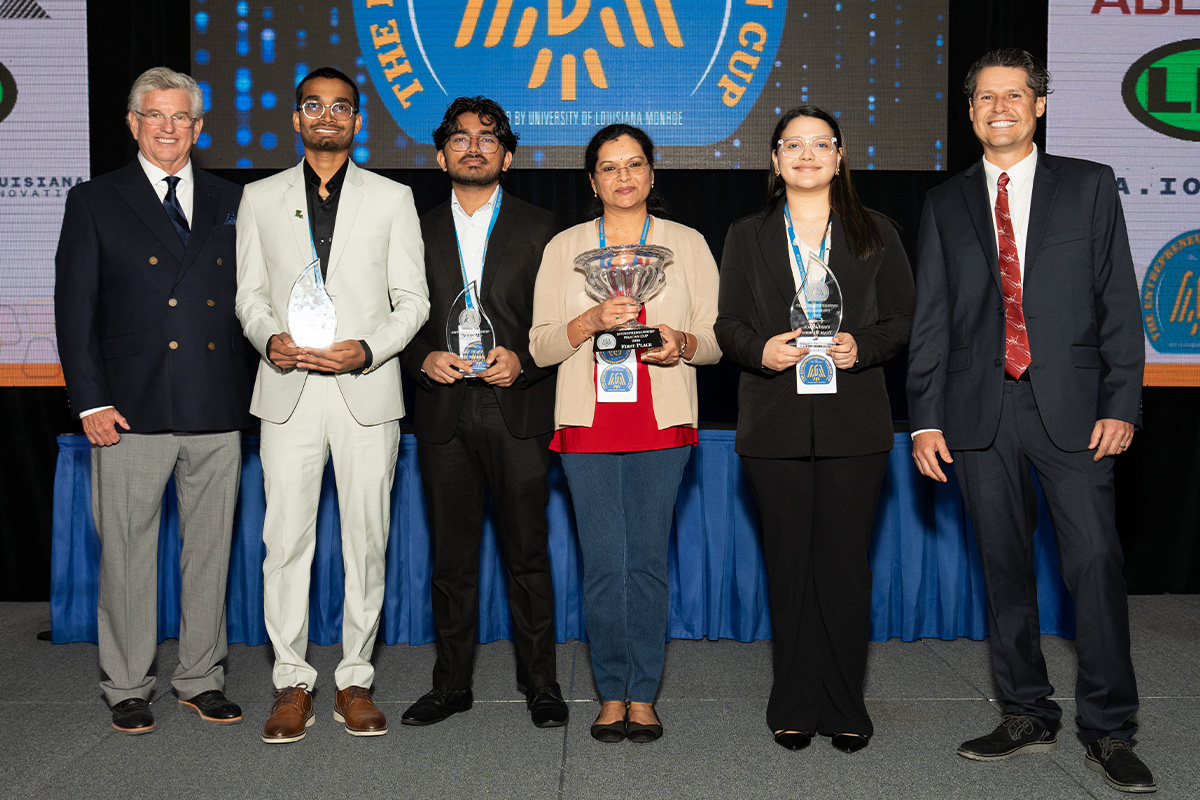 A group of people standing in a row holding trophies.