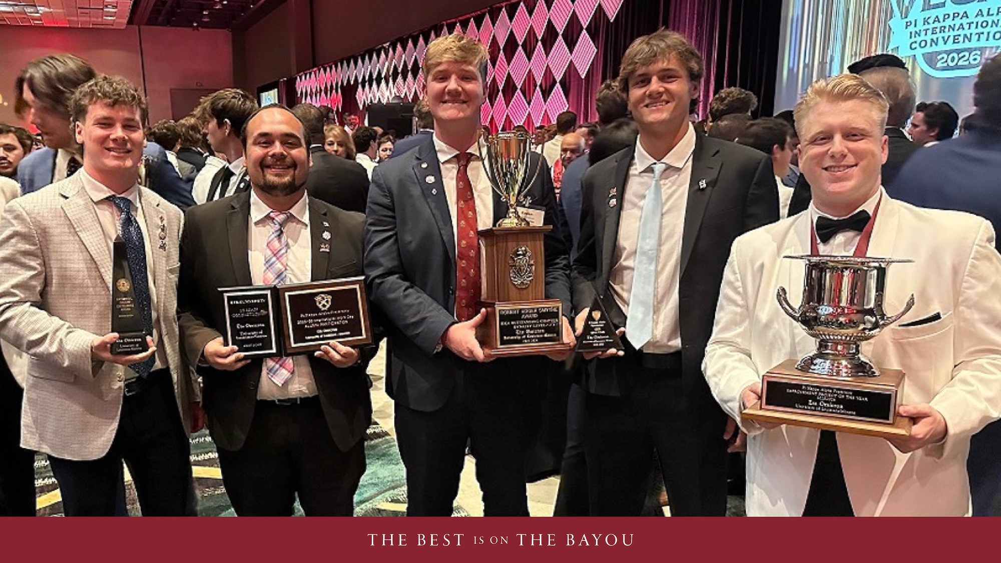 A group of students stand holding awards and smiling.