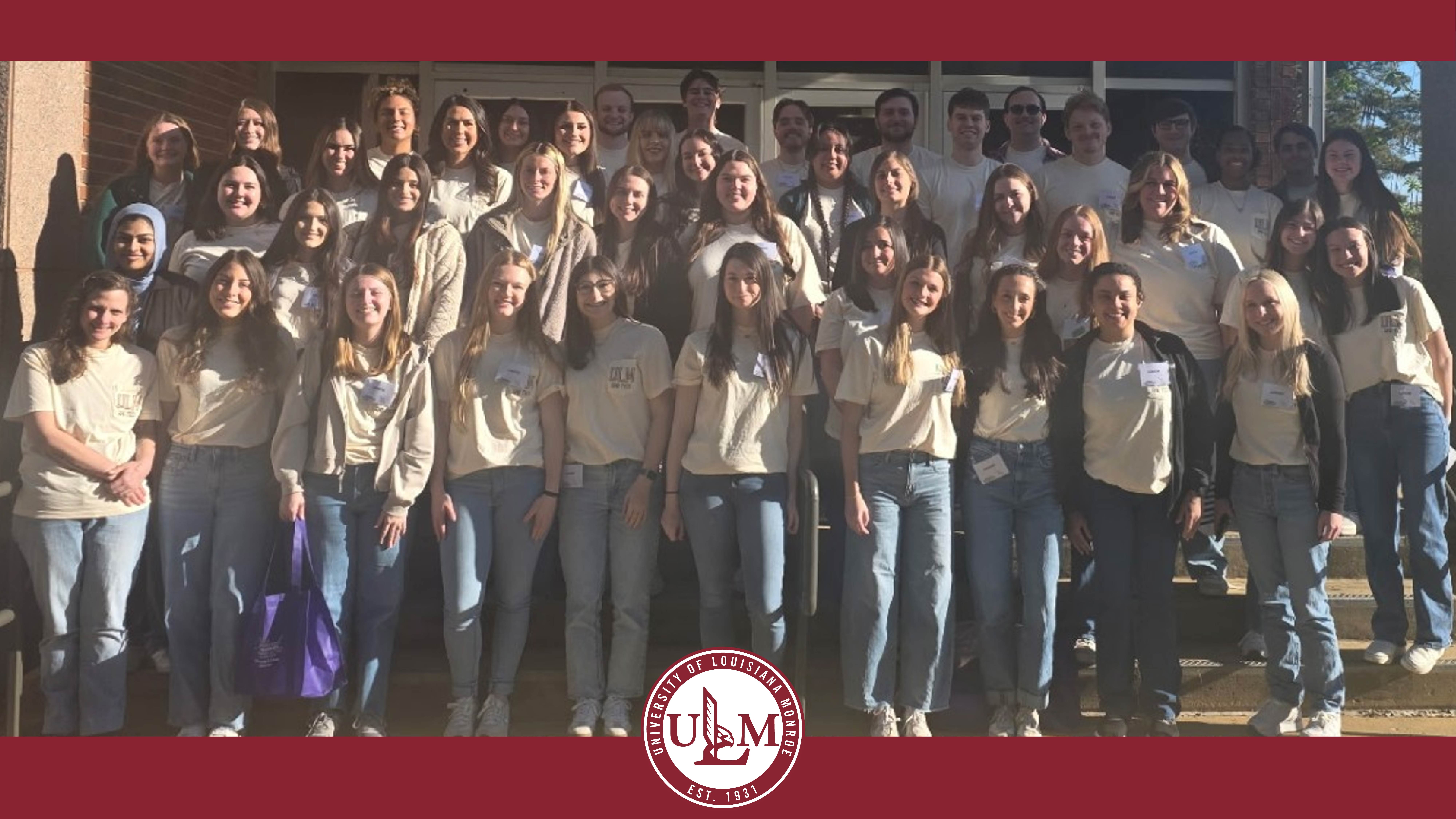 A group of students stand in smile in tiered rows.