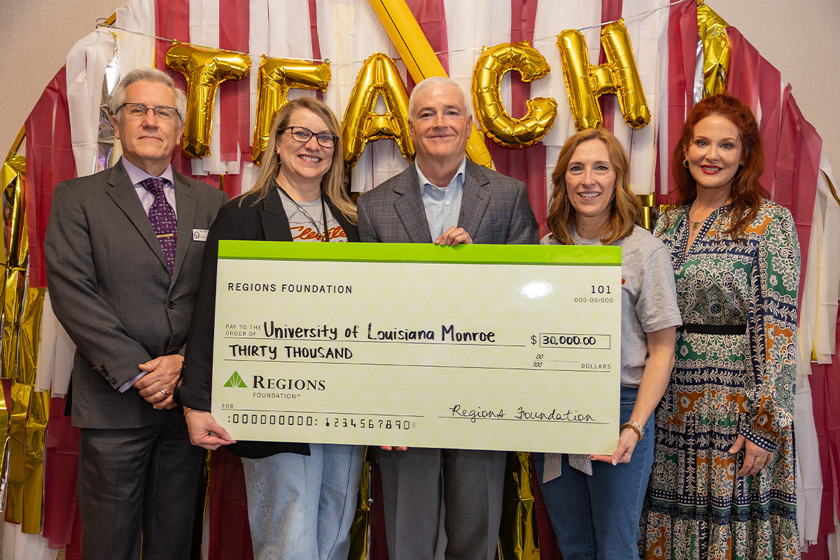 A group of people from ULM and the Regions Foundation hold a large check and smile. 
