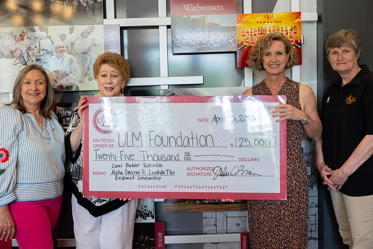 Four women pose with a large check for the creation of a scholarship.