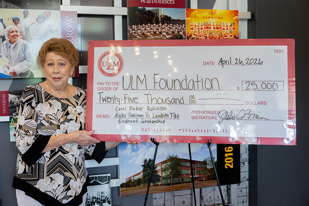 Carol Baker Robinson poses with a large check for an endowed scholarship in her name.