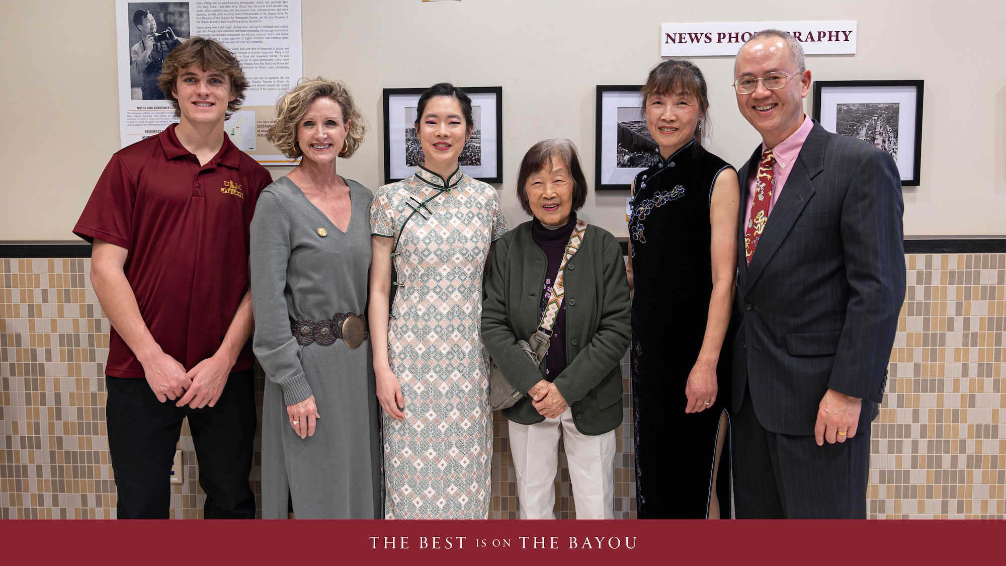 A group of people smiling in front of a photo exhibit. 