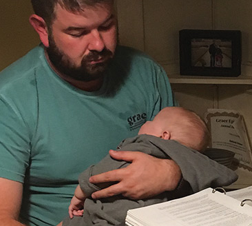 photo of student studying while holding baby