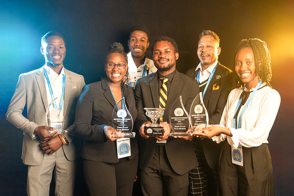 A group of six people are standing together, holding awards.