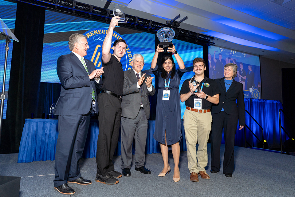 A group of people are standing on a stage, holding trophies.