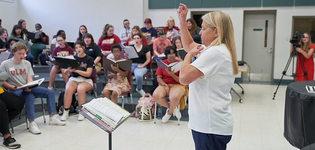 A woman directs a choir.