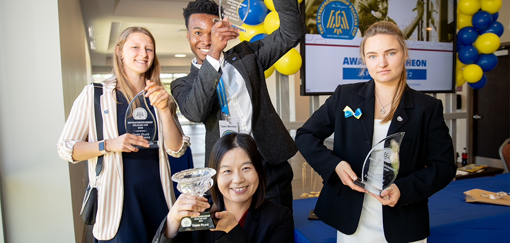 Four people smile at the camera holding awards.