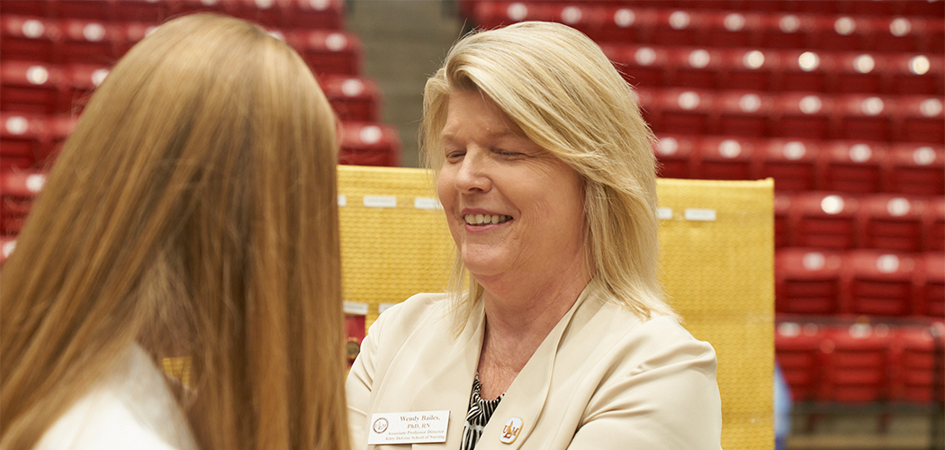 A woman pins something to another person's shirt.