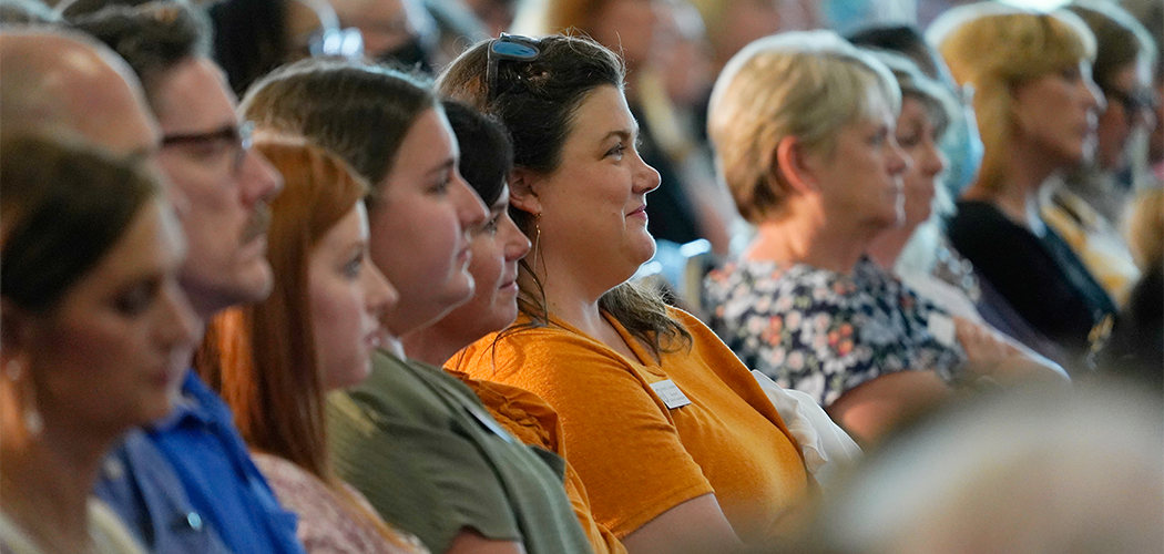 A group of people sit in a line, smiling toward the right.